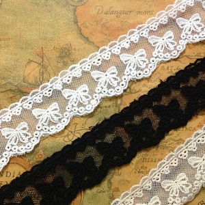 Puede incluir: Tres piezas de encaje blanco y negro con un patrón de lazo. El encaje está sobre un fondo marrón con un mapa.