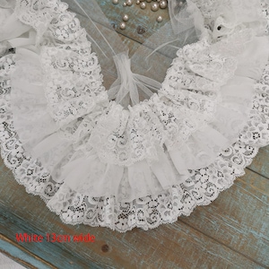 May include: White lace trim with three layers of ruffles. The trim is 1.3 inches wide.