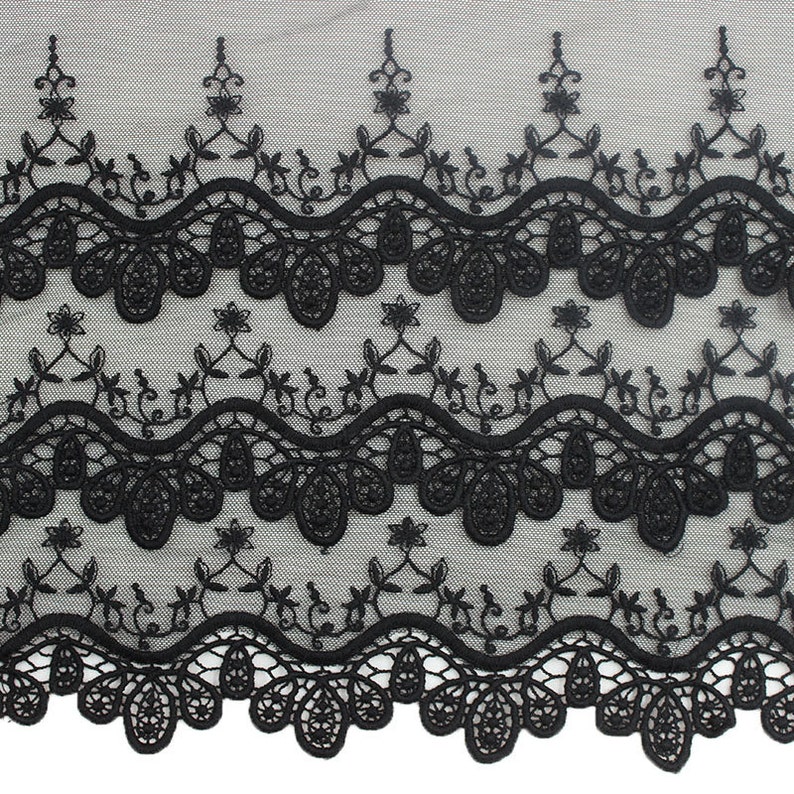 May include: Black lace trim with a scalloped edge and floral embroidery. The lace has a delicate, intricate design.