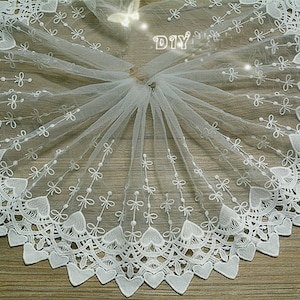 May include: White lace trim with a delicate heart pattern and small bows. The lace is sheer and has a soft, flowing texture.