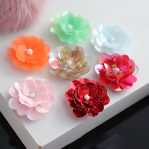 May include: Assortment of colourful flower-shaped sequins, including pink, orange, red, green, and white. These sequins are perfect for adding a touch of sparkle to crafts, clothing, and accessories.