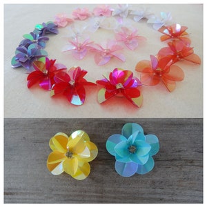 Puede incluir: Surtido de lentejuelas iridiscentes en forma de flor en varios colores, incluyendo rosa, rojo, azul y amarillo. Las lentejuelas están dispuestas en círculo y sobre una superficie de madera.