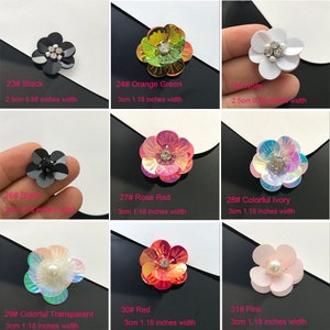 Peut inclure: Assortiment de dix embellissements en forme de fleur dans différentes couleurs, notamment noir, vert orange, blanc, rouge rose, ivoire coloré, transparent coloré, rouge et rose. Chaque fleur mesure 2,5 cm ou 3 cm de largeur.