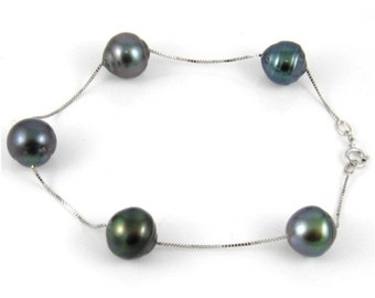 Op de afbeelding: Een zilveren kettingarmband met vier donkergroene parels.