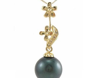 Puede incluir: Un collar de oro con un colgante de perla negra. El colgante presenta dos pequeñas flores doradas con diamantes, una encima de la otra, y una flor más grande encima de la perla.