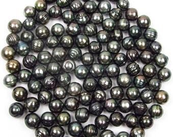 May include: A collection of dark green and black pearls, with iridescent highlights. The pearls are round and smooth, and they are arranged in a circular pattern.