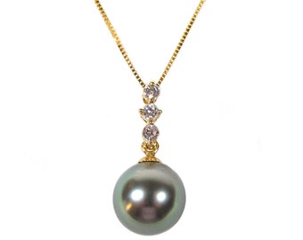Puede incluir: Un collar de cadena dorada con un colgante de perla gris oscuro grande y tres pequeñas piedras de circonita cúbica transparentes.