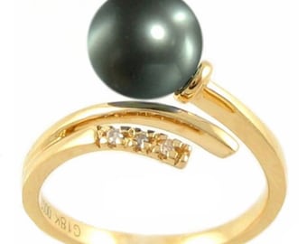 Puede incluir: Un anillo de oro con una perla negra y pequeños diamantes. El anillo está hecho de oro de 18 quilates y tiene un diseño único.