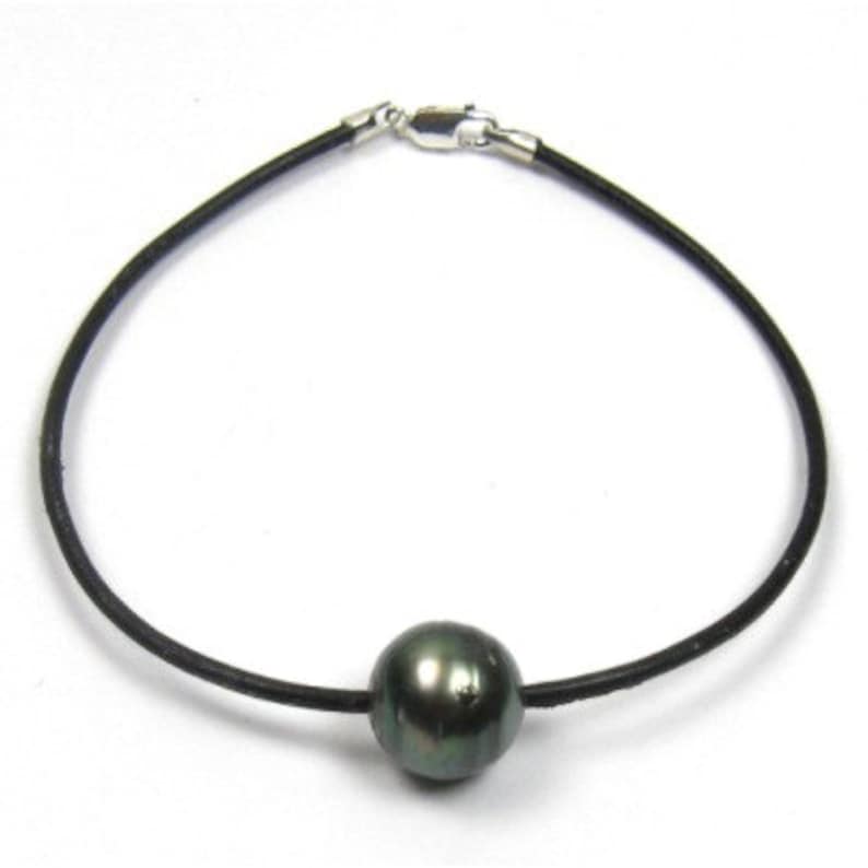 May include: A black leather cord bracelet with a single dark green pearl.