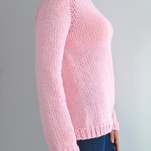 Puede incluir: Un su&eacute;ter de punto rosa con mangas largas y cuello redondo.