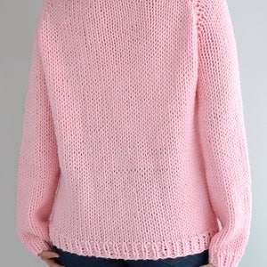 Puede incluir: Un su&eacute;ter de punto rosa con mangas largas y cuello redondo.