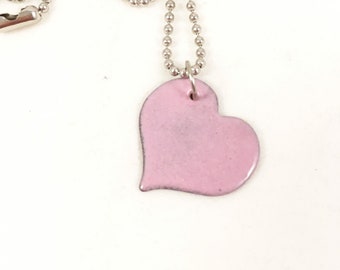 May include: A silver chain necklace with a pink heart pendant.