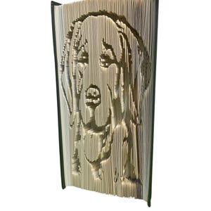 Peut inclure: Une œuvre d'art unique en livre représentant le visage d'un chien sculpté dans les pages. La silhouette du chien est créée en coupant et pliant avec précision les pages d'un livre, mettant en valeur un design créatif et artistique.