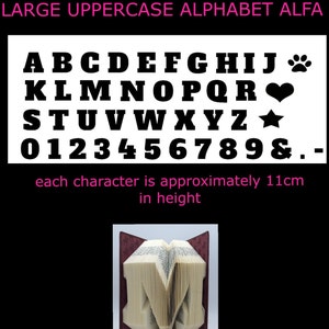 May include: A white background with a black uppercase alphabet, numbers, and symbols. Each character is approximately 11 cm tall. The word "ALFA" is written in pink at the top of the image. Below the alphabet is a picture of a book folded into the shape of the letter "M".
