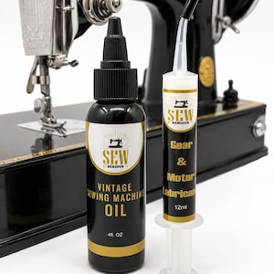 Könnte beinhalten: Eine schwarze Flasche Sew Serious Vintage Sewing Machine Oil mit 4 fl. oz. Etikett und eine transparente Spritze mit Sew Serious Gear & Motor Lubricant mit 12ml Aufschrift vor einer schwarzen, alten Nähmaschine.