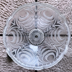 Könnte beinhalten: Eine transparente Glas-Deckenleuchte mit einem dekorativen, geätzten Muster aus Blättern und Kreisen.