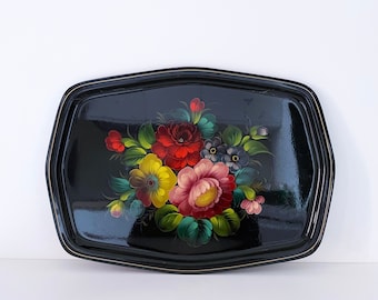 May include: A black metal serving tray with a gold rim and a hand-painted floral design. The flowers are red, pink, yellow, and blue.