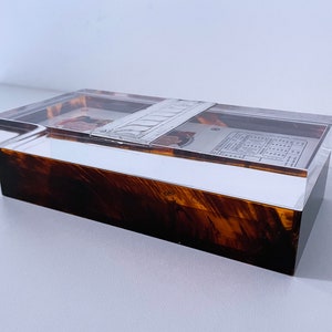 May include: A clear acrylic box with a brown wood base. The box contains a collection of vintage baseball cards.