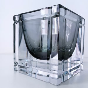 Op de afbeelding: Een glazen kom met een vierkant, geometrisch ontwerp. De kom heeft een donkergrijze binnenkant.