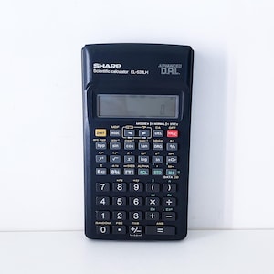Könnte beinhalten: Ein schwarzer Sharp EL-531LH wissenschaftlicher Taschenrechner mit einer Digitalanzeige, die "0" anzeigt. Der Rechner hat zahlreiche Tasten für verschiedene mathematische Funktionen und ist mit "ADVANCED D.A.L." beschriftet.