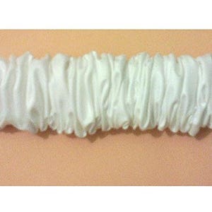 May include: White satin elastic with a gathered, ruffled design. The elastic is approximately 1 inch wide.