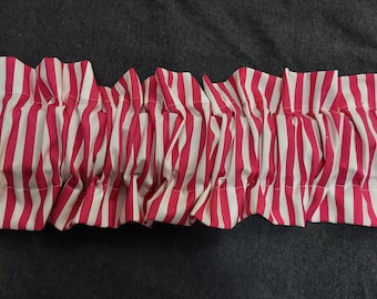 May include: A pink and white striped fabric valance with a ruffled edge.