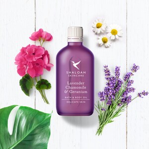 Peut inclure: Bouteille violette d'huile de bain et de corps avec le texte "Shaloah Skincare Lavender Chamomile & Geranium Bath & Body Oil Delicate Skin". La bouteille est entour&eacute;e de fleurs de lavande, de camomille et de g&eacute;ranium.