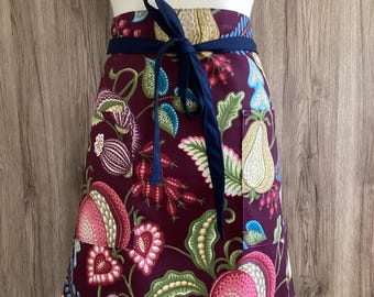 Bordeaux red half apron with long straps and two pockets. 100% cotton fabric. Fruits and leaves. Green, red, blue, yellow.