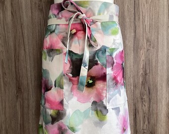 Wide and long half apron with two pockets and long straps. Large pink flowers in a thick and soft cotton fabric.
