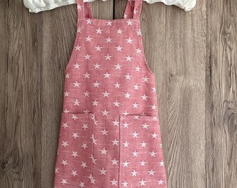 Toddler apron. 18 - 36 months. Children’s cross back apron in pink with white stars. Two pockets. No tie apron for 1.5 - 3 year olds.