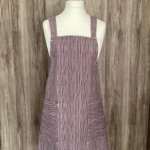 May include: A purple and white striped apron with two large pockets. The apron has adjustable straps.