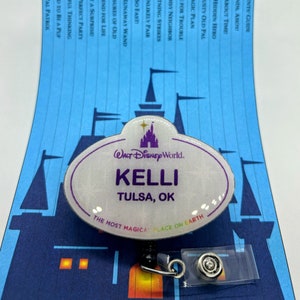 May include: A white plastic name tag with a silver glitter finish. The tag features the Walt Disney World logo and the text "KELLI TULSA, OK" and the phrase "The Most Magical Place on Earth".