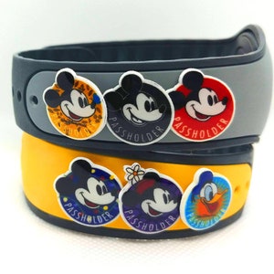 May include: Two gray and yellow Mickey Mouse wristbands with Mickey Mouse character stickers. The stickers have the word "Passholder" printed on them.