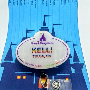 May include: A white oval name tag with the text "WALT DISNEY WORLD" in black, "KELLI" in rainbow colors, and "TULSA, OK" in black. The tag has a blue and white castle graphic and the text "THE MOST MAGICAL PLACE ON EARTH" in black.