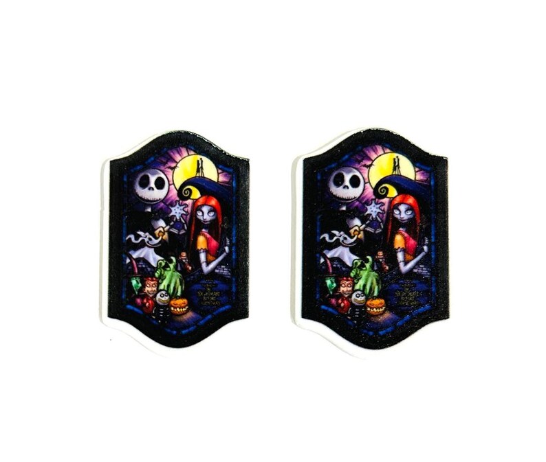 Może przedstawiać: Dwa pasujące, dekoracyjne elementy w kształcie tarczy z kolorową ilustracją Jacka Skellingtona i Sally z Miasteczka Halloween. Grafika zawiera pełnię księżyca i r&oacute;żne postacie.