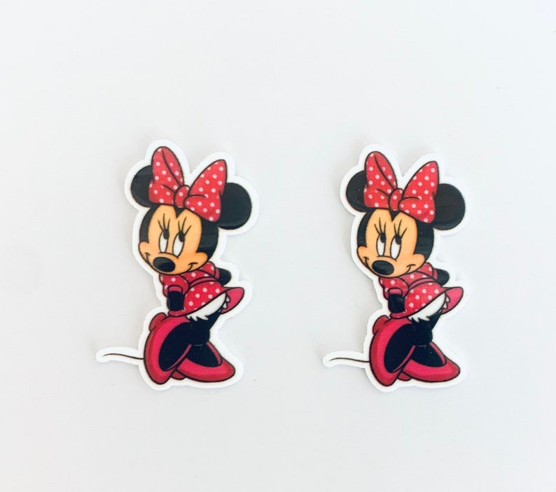 May include: Two red and white polka dot Minnie Mouse stickers with black outlines. The stickers are on a white background.
