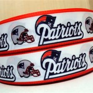 Pode incluir: Fita branca e vermelha com um padr&atilde;o repetido de um capacete de futebol americano e a palavra "Patriots" em letras azuis.