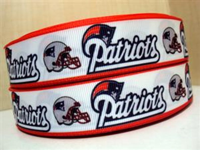 Pode incluir: Fita branca e vermelha com um padr&atilde;o repetido de um capacete de futebol americano e a palavra "Patriots" em letras azuis.