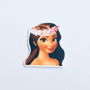 Op de afbeelding: Een sticker met een cartoonillustratie van een vrouw met bruin haar, bruine ogen en een roze bloemenkrans. De vrouw heeft een lichte huidskleur en een zachte glimlach. De sticker is uitgesneden rond de omtrek van de afbeelding.