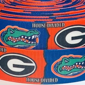 May include: Red and blue ribbon with a repeating pattern of the University of Georgia 'G' logo and an alligator head. The text 'House Divided' appears on the ribbon.