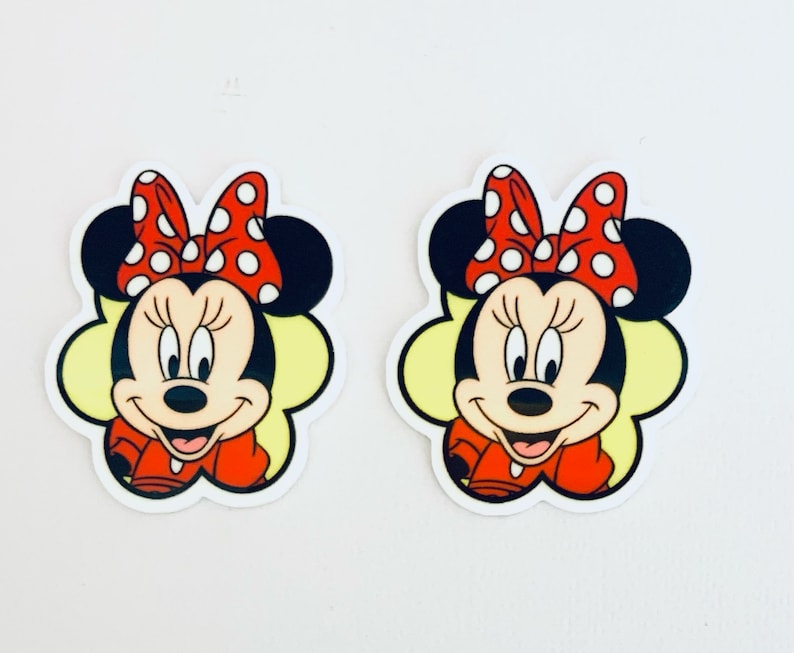 May include: Two cartoon Minnie Mouse stickers with red polka dot bows and yellow backgrounds.
