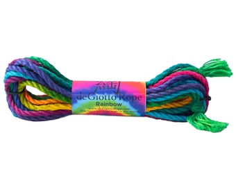 Op de afbeelding: Een regenboogkleurig touw gemaakt van natuurlijke vezels. Het touw is in een knoop geknoopt en heeft een label met de tekst "deGiotto Rope Rainbow www.deGiottoRope.com The finest heritage rope in the world."