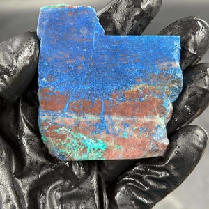 May include: A rough, irregular shaped slab of blue and brown chrysocolla with green accents. The stone has a layered, banded appearance.