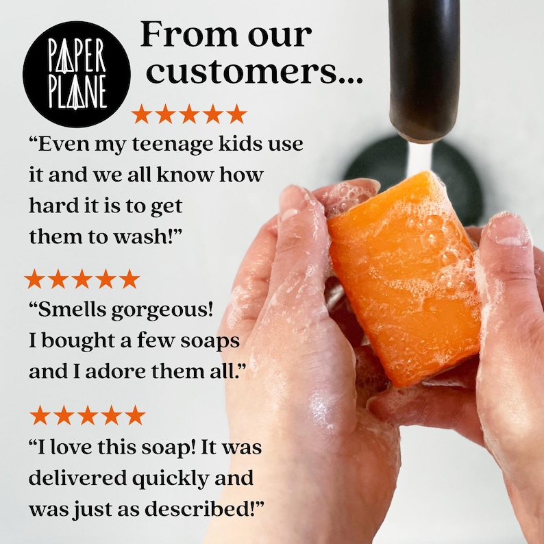 May include: A close-up of a person's hands washing an orange bar of soap with water running from a faucet. The soap is labeled "Paper Plane" and has five-star reviews with customer testimonials. The text reads: "Even my teenage kids use it and we all know how hard it is to get them to wash!" "Smells gorgeous! I bought a few soaps and I adore them all." "I love this soap! It was delivered quickly and was just as described!"