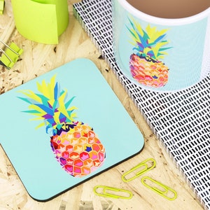 May include: A turquoise blue coaster with a colorful geometric pineapple design. The pineapple is made up of yellow, orange, pink, red, blue, and green colors.