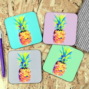 May include: Four square coasters with a geometric pineapple design. The pineapples are in shades of yellow, orange, blue, and green. The coasters are on a wood background.