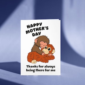 Puede incluir: Tarjeta blanca del Día de la Madre con una ilustración de dibujos animados de dos monos abrazándose. El texto "Happy Mother's Day" está en la parte superior y "Thanks for always being there for me" en la inferior.