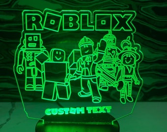 May include: Green LED night light with a custom text option. The design features the word "ROBLOX" and several characters from the game.