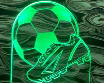 May include: Green LED night light with a soccer ball and a soccer cleat design. The light has a space for a custom name, which says "CUSTOM NAME".