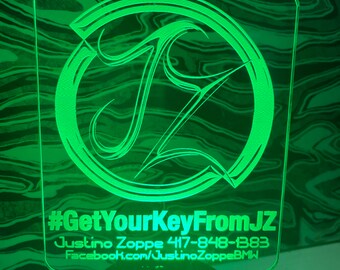 May include: Green acrylic sign with a stylized letter "J" in a circle. The sign reads "#GetYourKeyFromJZ Justino Zoppe 417-848-1383 Facebook.com/JustinoZoppeBMW"